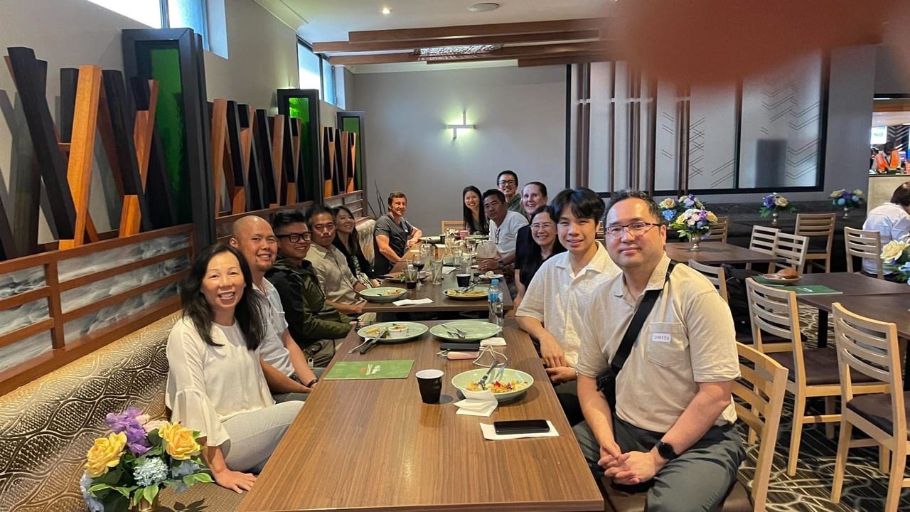Attendees and panelists smiling around a long table at a shared meal